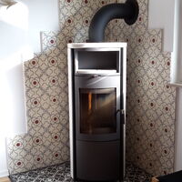 Zementfliesen mit Dekor auf dem Boden (schwarz-weiß) und ander Wand (rot-weiß) in einer Ecke mit Ofen