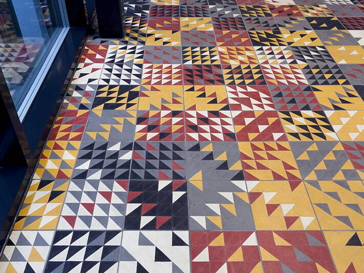Designfliesen mit Dreiecken in verschiedenen Farbkombinationen verlegt auf dem Boden vor einem Fenster